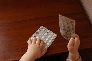 el niño tomó fuera pastillas, el niña es jugando con médico medicamento, un un año de edad niño lata comer pastillas y no despertar arriba, veneno. peligro en el casa, medicamentos son peligroso para joven niños. foto