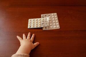 The child took out pills, the girl is playing with medical medicine, a one-year-old child can eat pills and not wake up, poison. Danger in the house, medicines are dangerous for young children. photo