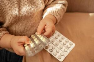 el niño tomó fuera pastillas, el niña es jugando con médico medicamento, un un año de edad niño lata comer pastillas y no despertar arriba, veneno. peligro en el casa, medicamentos son peligroso para joven niños. foto