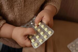 el niño tomó fuera pastillas, el niña es jugando con médico medicamento, un un año de edad niño lata comer pastillas y no despertar arriba, veneno. peligro en el casa, medicamentos son peligroso para joven niños. foto