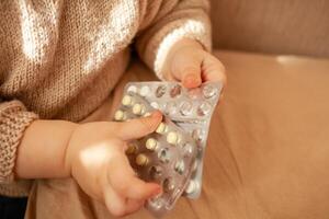 el niño tomó fuera pastillas, el niña es jugando con médico medicamento, un un año de edad niño lata comer pastillas y no despertar arriba, veneno. peligro en el casa, medicamentos son peligroso para joven niños. foto