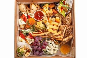 A box of food, cheese, breads, fish, shrimp. Food delivery for the company, romantic, office dinner at home. Beautiful composition of food in a box, convenient carrying, fresh products. photo