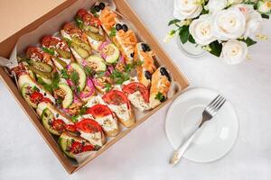 Delivery of food in a box, delicious and fresh food. Convenient boxing for eating at home, at work, in nature. Bruschetta with salmon, cheese, beetroot, nuts photo