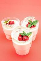 Sweet dessert in glass with biscuit,berry fruit and whipped cream. Empty space for text on a pink background photo