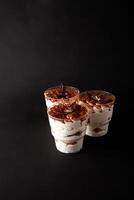 Sweet dessert in glass tiramisu on a black background in a low key. Empty space for text photo