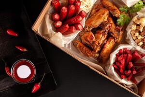 Red peppers on a black background in a low key. Food delivery from markets and restaurants. Meal for a week on quarantine. Chicken wings, shrimp crackers sausages to beer at the craft box photo