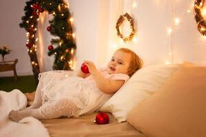 un pequeño niña en un Navidad foto estudio. boke, amarillo luces, contento bebé