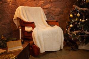 New Year's photo zone in the studio. A chair, a Christmas tree with balls and cones. Yellow garland, lights, candles, lamps, books. Home interior for Christmas.