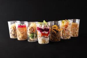 Different salads and snacks in plastic cups, studio photo. Catering, food delivery photo