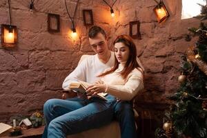 A couple in love, a guy and a girl reading a book. Christmas decorations in the photo studio Young teens