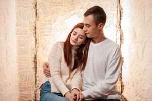 un joven Pareja en amor se sienta en un balancearse. posando para modelos en un foto estudio. el chico y el niña amor cada otro, abrazo