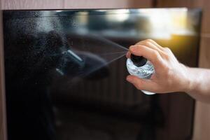 The man cleans the TV from the dust with a alcohol solution photo