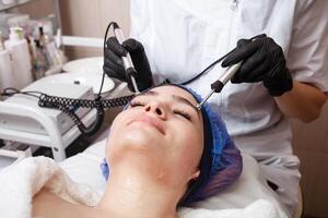 The beautician performs the microcurrent procedure in the beauty salon. photo