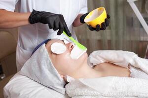 The beautician makes an alginite mask in the beauty salon photo