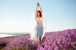 A young beautiful girl stands in full height in a lavender field photo