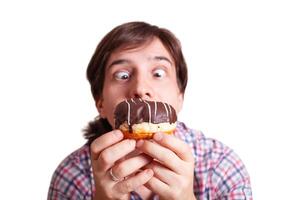 gracioso hombre mira a el chocolate rosquilla abultado ojos foto