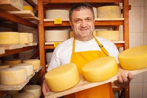 Cheese seller in store, home production, business, entrepreneur. Smiling man, portrait. Businessman, sale of cheese products. Made with love and care. holds in his hands photo