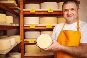 queso vendedor en almacenar, hogar producción, negocio, emprendedor. sonriente hombre, retrato. empresario, rebaja de queso productos hecho con amor y cuidado. creativo creación foto