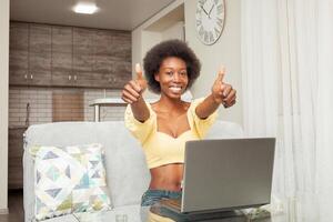 Portrait of African American woman, smiling happy, super, cool, thumbs up, laptop work at home. photo