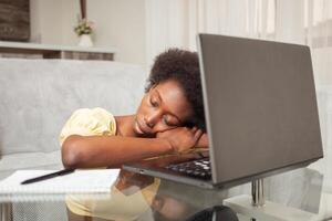 African American black woman freelancer sleeps in workplace near laptop, working at home, tired. photo