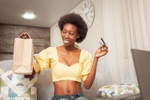 African American black woman at home sitting in front of laptop, online shopping, home delivery, bank card. Discounts promotions in the store. holiday gift photo