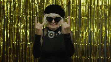 Excited positive senior woman showing rock and roll gesture and sincerely smiling, showing tongue video