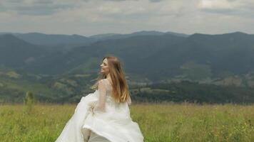 Beautiful bride in wedding dress running through the mountains hills video