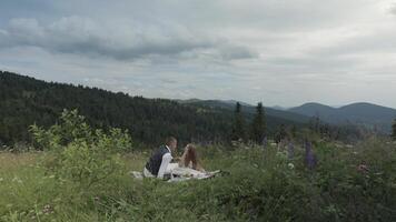 Groom with bride having a picnic on a mountain hills. Wedding couple. Family video