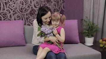 pequeño hija y madre sentado en sofe con ramo de flores de lila púrpura flores video