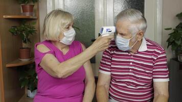 Grandfather and grandmother measures temperature with electronic thermometer. Coronavirus, Covid-19 video