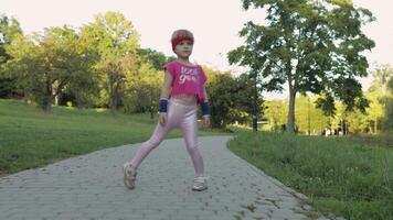 Young cute child girl in sportswear making fitness exercises outdoors in park. Workout for kids video