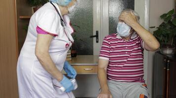 Nurse measures temperature with non-contact electronic thermometer of sick grandfather. Coronavirus video