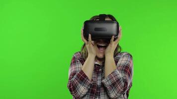 Girl using VR app helmet to play simulation scary game. Woman watching virtual reality 3D video