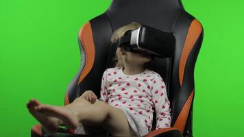 Child girl using VR helmet to play simulation game app. Watch virtual reality 3d video. Chroma key video