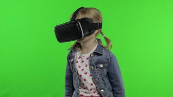 Child girl using VR app helmet to play simulation game, drawing. Watching virtual reality 3d video