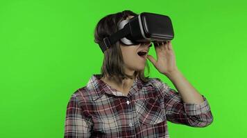 Young girl using VR app helmet to play simulation game. Woman watching virtual reality 3d video