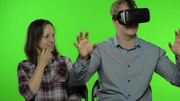 Man and woman using VR headset helmet to play game. Watching virtual reality 3D video. Chroma key video