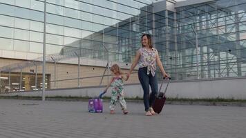 madre y hija caminando desde aeropuerto. mujer y niño que lleva maleta bolsas. mamá después vacaciones video