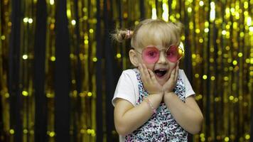 niño baile, espectáculo asombro, engañando alrededor, sonriente. niña posando en antecedentes con frustrar cortina video