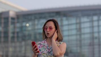 content femme touristique dans branché des lunettes de soleil dansant et écoute à la musique dans casque de musique utilisation téléphone intelligent video