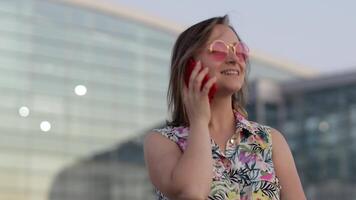 niña en de moda Gafas de sol hablando en móvil teléfono. haciendo llamada en teléfono inteligente vacaciones, turismo video