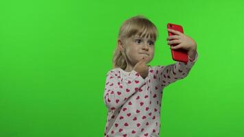 Kid girl using smartphone. Child emotionally makes selfie on mobile phone. Video call, blog, game