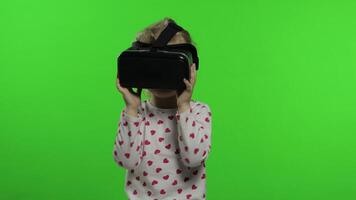 Child girl using VR helmet to play simulation game app. Watch virtual reality 3d video. Chroma key video