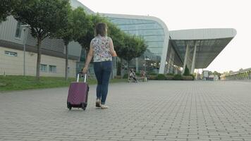 empresária viajante caminhando com bagagem para aeroporto. menina anda em e rolos mala de viagem bolsa. turismo video