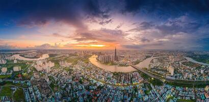 aéreo puesta de sol ver a punto de referencia 81 - eso es un súper alto rascacielos y saigon puente con desarrollo edificios a lo largo saigon río, paisaje urbano en el noche foto