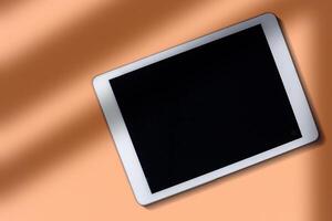 Digital tablet mockup screen over plane surface on Peach Fuzz color of the year. Top view header with copy space and blank screen. photo