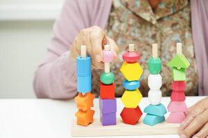 Asian elderly woman playing puzzles game for treatment dementia prevention and Alzheimer disease. photo