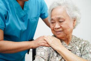 Caregiver help Asian elderly woman disability patient sitting on wheelchair in hospital, medical concept. photo