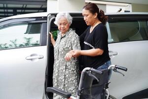 Caregiver help Asian elderly woman disability patient get in her car, medical concept. photo