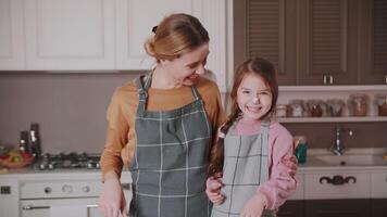 tandis que fabrication une gâteau, maman en plaisantant frottis sa fille nez avec crème. et elles ou ils rire. une peu cuisiner. réel et vif émotions. content famille. video